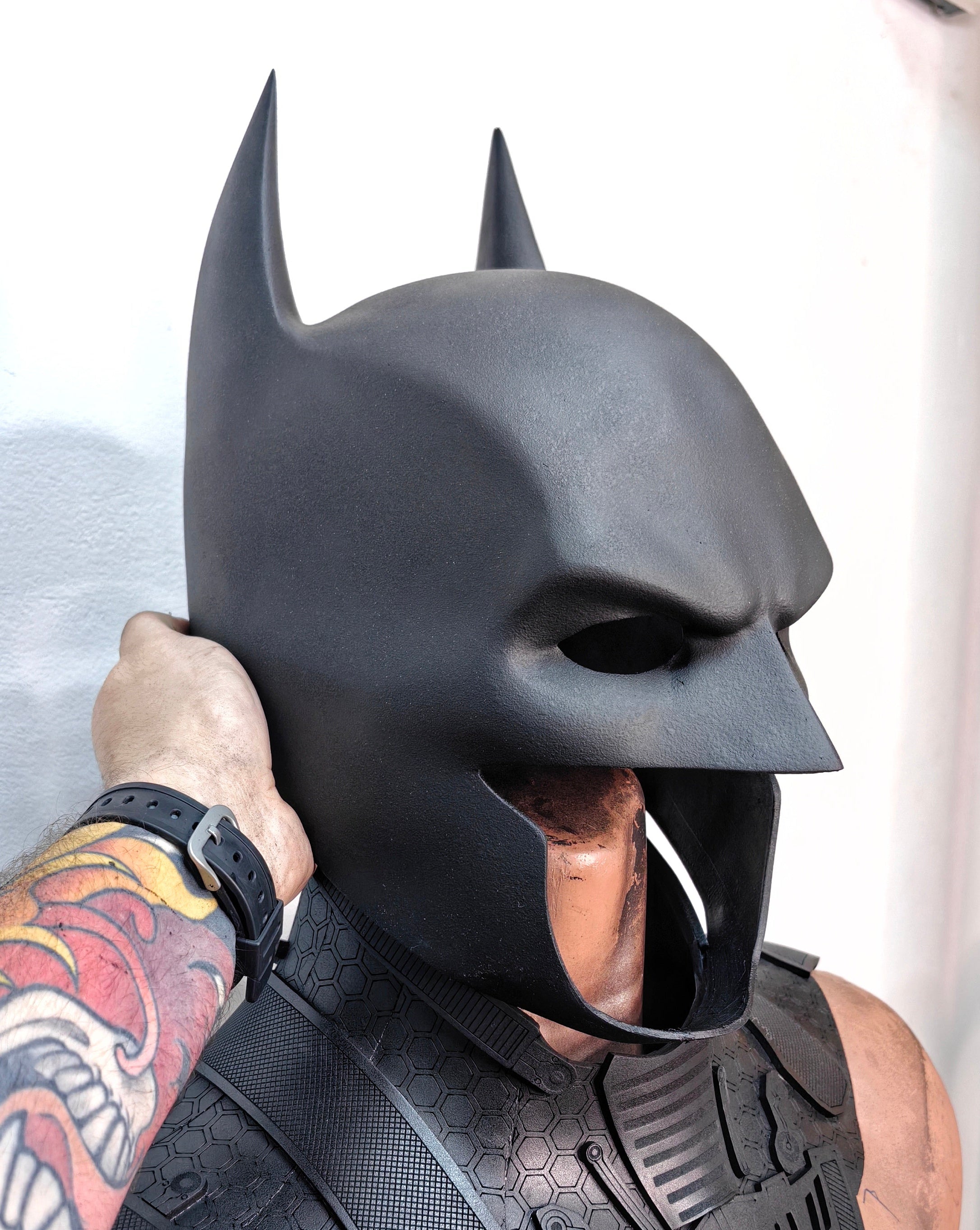 Front view of a classic Batman cowl with a sleek matte black finish and sharp brow definition.
