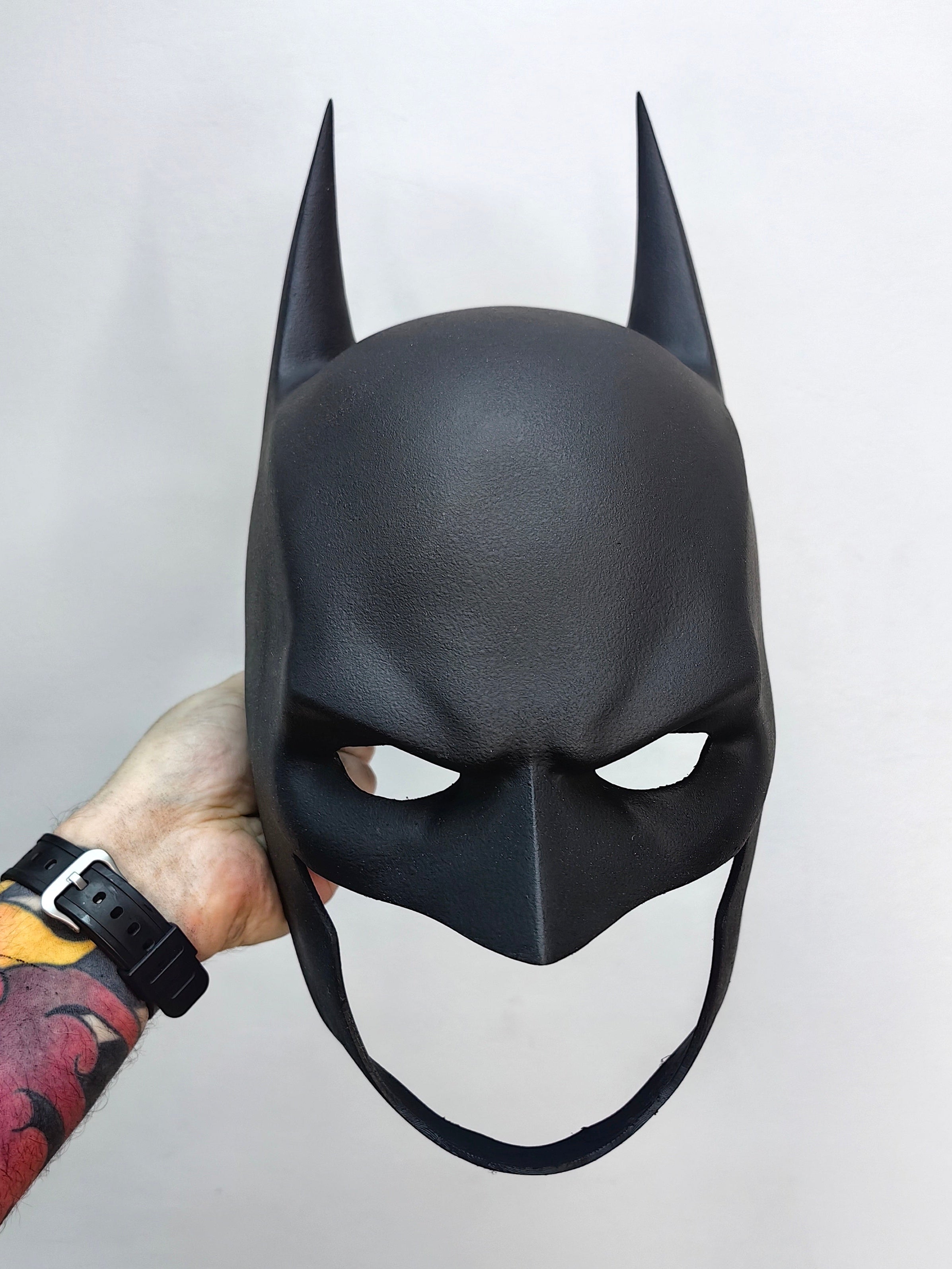 High-quality handmade Batman cowl held in hand to demonstrate scale and professional craftsmanship.