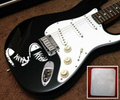 A white vinyl guitar sticker with a design resembling sneakers applied on a black electric guitar, with a close-up of the sticker's texture shown in a inset.